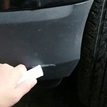 A black plastic bumper with visible scratches being sanded down with a fine grit sandpaper.